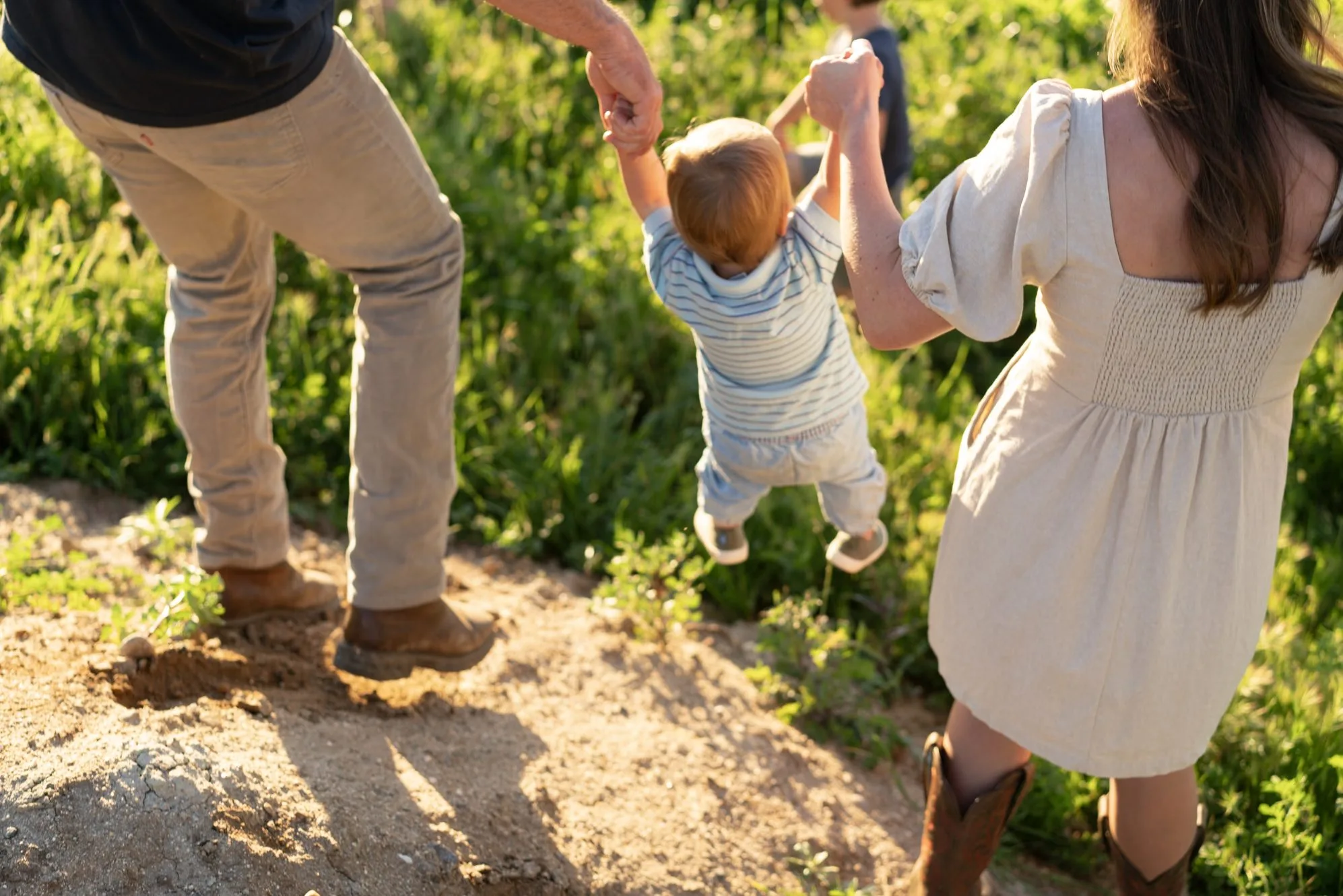 Kids swinging between their parents on the ranch road