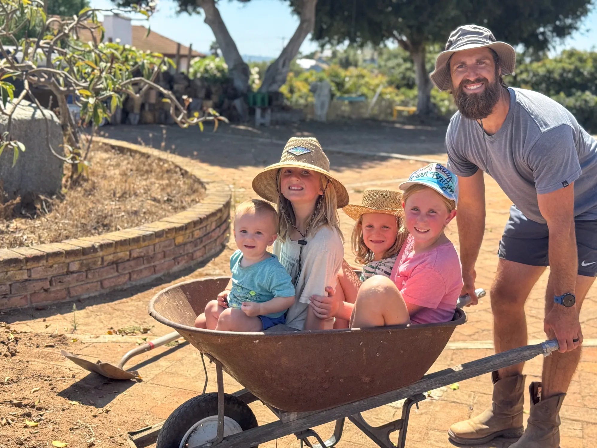 Dad and the kids loaded into a wheelbarrow by the garden wall